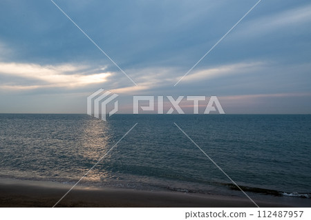 Tranquil Seascape with Sun Rays Piercing Through Clouds 112487957