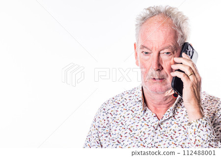 Senior Man in Thoughtful Conversation Over the Phone 112488001