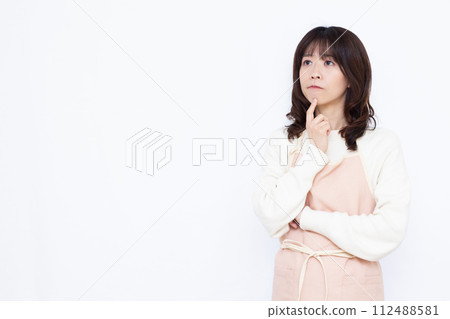A housewife wearing an apron thinking seriously A housewife wearing an apron thinking seriously 112488581