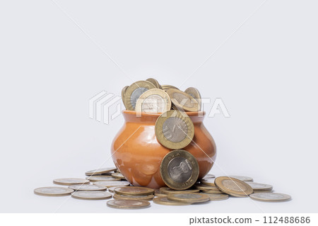 Coins in a clay pot on a white background with copy space. 112488686