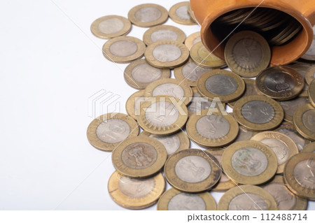 Coins falling out of a pot on a white background with copy space. Business concept. Coins falling out of a pot on a white background with copy space. Business concept. 112488714