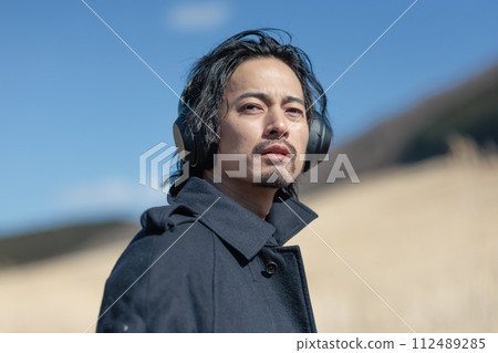 一個30多歲的男人在草地上聽音樂 112489285