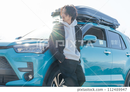 一名30多歲的男子開車時在停車場與自己的車合影留念 一名30多歲的男子開車時在停車場與自己的車合影留念 112489947