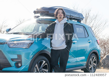 一名30多歲的男子開車時在停車場與自己的車合影留念 112489957