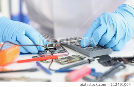 Master repairman inserting microchip into mobile phone closeup 112491004