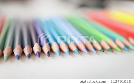 Many sharp multicolored pencils lying over colors of rainbow closeup background Many sharp multicolored pencils lying over colors of rainbow closeup background 112491038