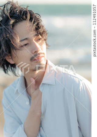一名30多歲的男子穿著白襯衫站在海邊 112491057