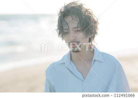 一名30多歲的男子穿著白襯衫站在海邊 112491066
