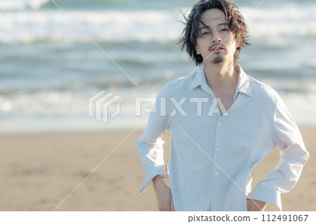 一名30多歲的男子穿著白襯衫站在海邊 112491067