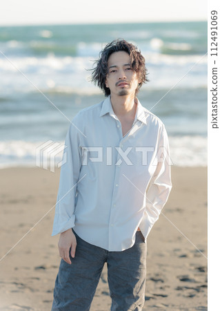 一名30多歲的男子穿著白襯衫站在海邊 112491069