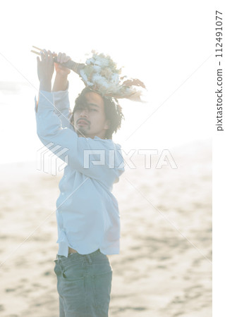 A man in his 30s wearing a white shirt standing by the seaside A man in his 30s wearing a white shirt standing by the seaside 112491077