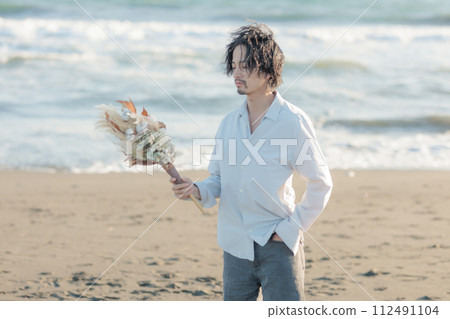 一名30多歲的男子穿著白襯衫站在海邊 112491104