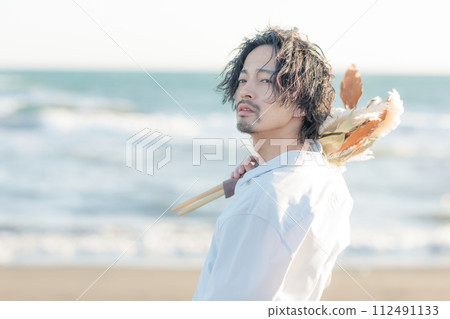 A man in his 30s wearing a white shirt standing by the seaside A man in his 30s wearing a white shirt standing by the seaside 112491133