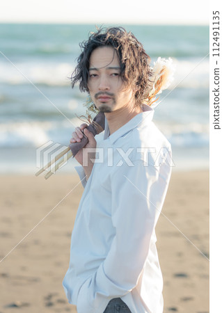 一名30多歲的男子穿著白襯衫站在海邊 一名30多歲的男子穿著白襯衫站在海邊 112491135