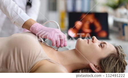 Doctor making ultrasound of thyroid gland to woman patient in clinic 112491222