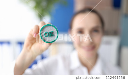 Woman holding green ink stamp OK in her hand closeup 112491236