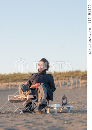 A man in his 30s having a bonfire at the beach A man in his 30s having a bonfire at the beach 112491393