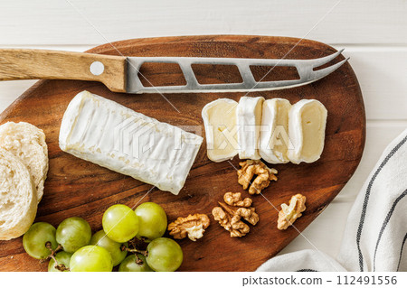 Sliced Brie cheese on a wooden board 112491556