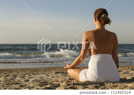 Woman meditating on beach 112492524