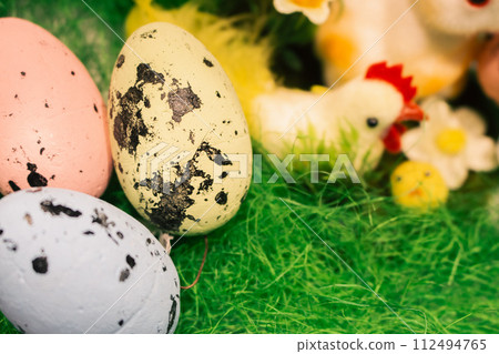 Easter eggs on green grass. Happy Easter decor. Springtime holidays. Easter toys and painted eggs. Traditional spring symbols. 112494765