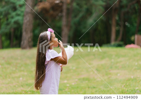 Adorable and pretty girl eating white sweet cotton candy. Happy child, kid eating sweets with emotions in the park at summer 112494909