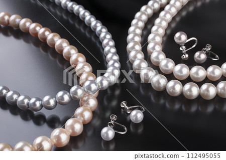 Pearl necklace and earrings on a black background 112495055