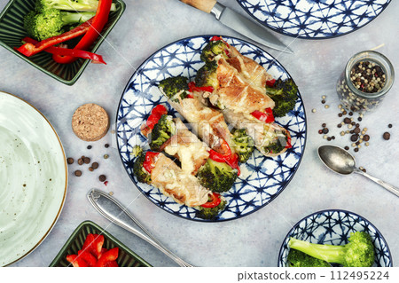 Meat rolls with broccoli and pepper on a plate. 112495224
