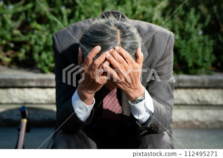 Senior man in suit, sitting, holding head 112495271