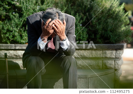 Senior man in suit, sitting, holding head 112495275