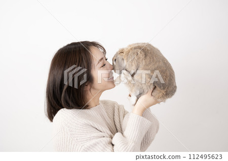 一個微笑的女人在白色背景下抱著一隻兔子 112495623