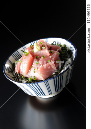 Photograph of bowl of chopped tuna against a black background 112496316