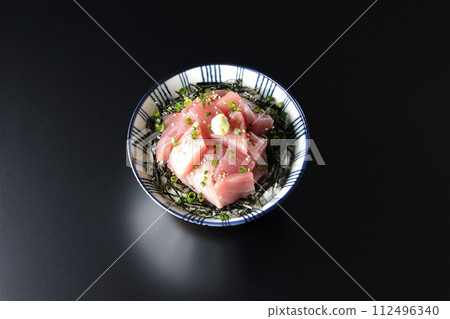 An overhead shot of a bowl of chopped tuna against a black background An overhead shot of a bowl of chopped tuna against a black background 112496340
