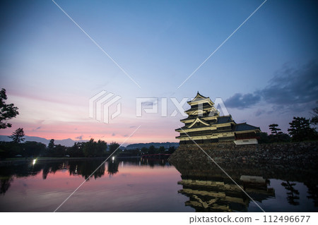 Matsumoto Castle at dawn and the sunrise reflected on the moat 112496677