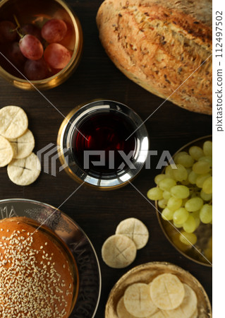 Bread, grapes in bowls and cup of wine on wooden background, top view 112497502