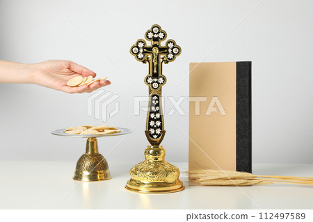 Cross, liturgical bread, hand and book on white background Cross, liturgical bread, hand and book on white background 112497589