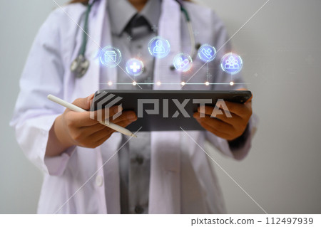 Female doctor in a white coat using digital tablet with virtual displays medical information icons 112497939