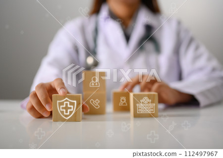 Doctor's hand touching wooden cubes with medical icon. Health Insurance concept Doctor's hand touching wooden cubes with medical icon. Health Insurance concept 112497967