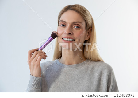 Pretty young blonde woman doing make up and smiling Pretty young blonde woman doing make up and smiling 112498075