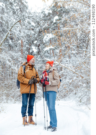 Man and woman with scandinavian sticks in a winter forest looking enjoyed 112498190