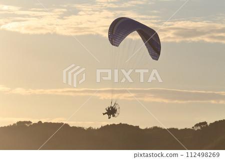 機動滑翔傘在黃昏時起飛至天空 機動滑翔傘在黃昏時起飛至天空 112498269