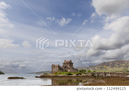 Eilean Donan Castle emerges from a Scottish loch, its bridge set against the Highland tapestry Eilean Donan Castle emerges from a Scottish loch, its bridge set against the Highland tapestry 112499125