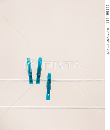 Two Blue Clothespins Are Hanging On A Clothes Line Against White background 112499131