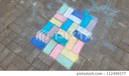 Children's drawing with colored crayons on paving slabs. The concept of the Children's Day holiday 112499377
