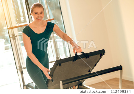 Flexible and slim woman doing stretching exercises on Pilates machine Flexible and slim woman doing stretching exercises on Pilates machine 112499384