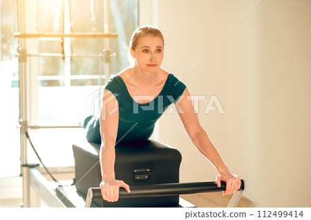 Flexible and slim woman doing stretching exercises on Pilates machine 112499414