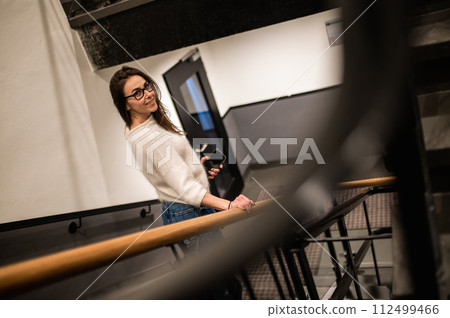 Confident woman wearing casual clothes walking on stairs in hotel 112499466