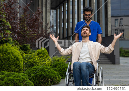 Male nurse rolling a wheelchair with patient and both feeling good 112499561