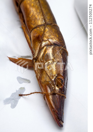 Smoked freshwater pike fish for home use on white paper.. Smoked freshwater pike fish for home use on white paper.. 112500274