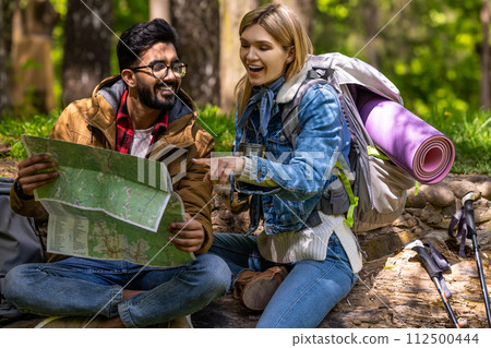 A couple of travelers scrutinizing the map and searching for a new route 112500444