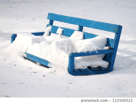 Winter background .Blue wooden bench covered with snow in the park. 112500522